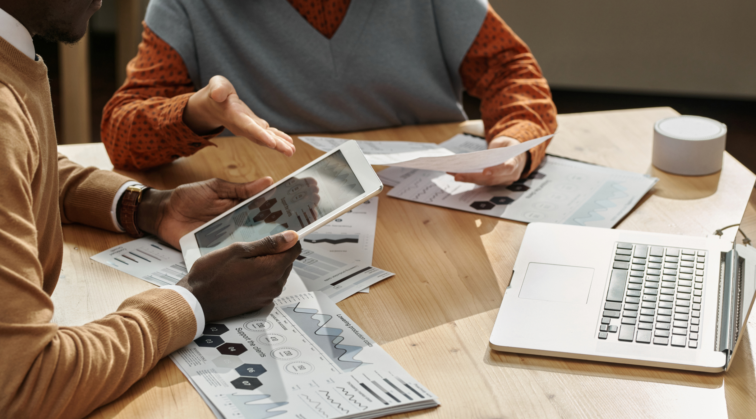 deux personnes qui regardent des diagrammes sur une tablette et des feuilles de papiers